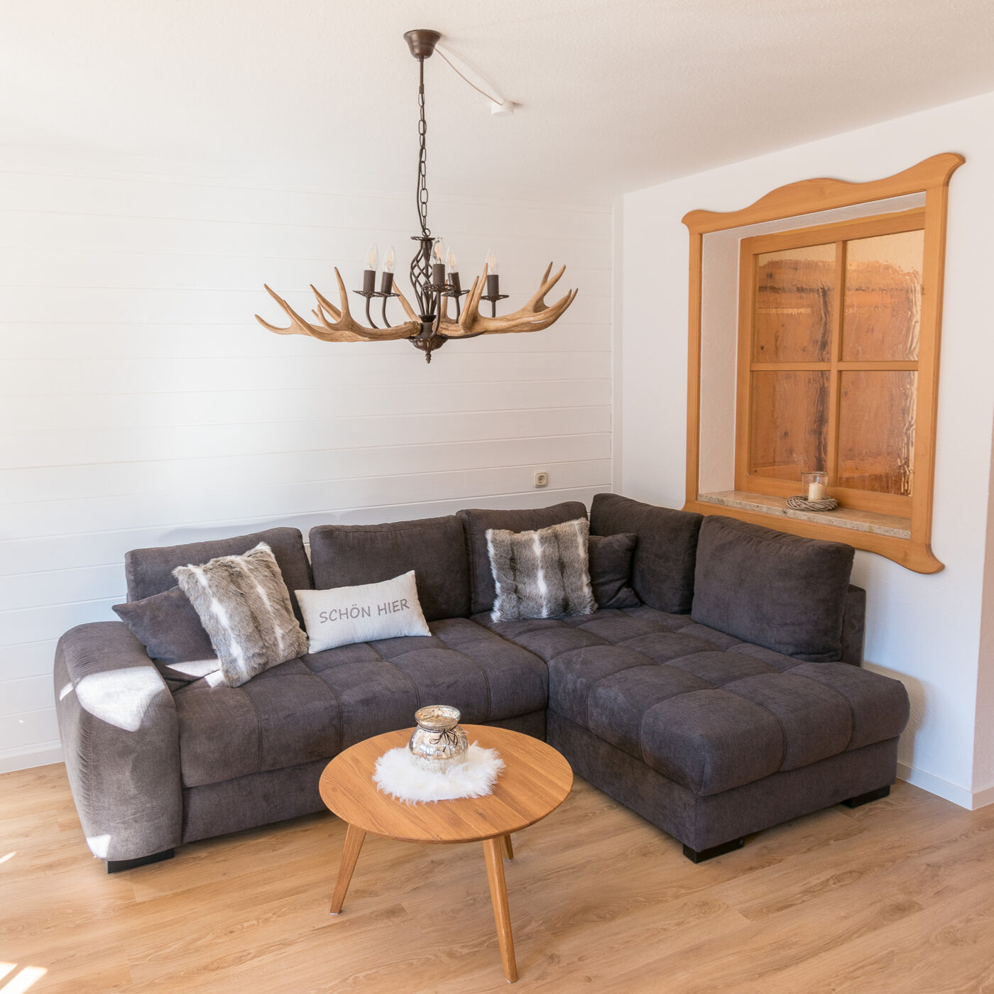 Wohnzimmer mit gemütlichem Sofa und Geweihleuchter